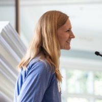 Alumna Laura Marshall speaking into microphone at celebration event